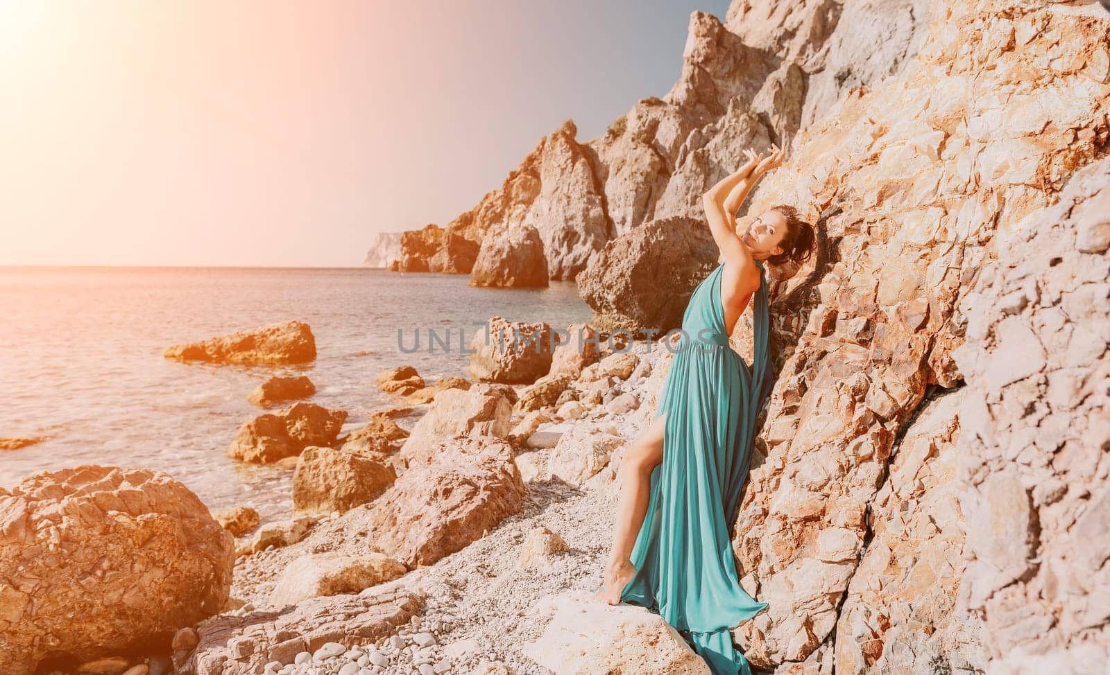 Side view a Young beautiful sensual woman with black hair in a long mint dress posing on a beach with calm sea bokeh lights on sunny day. Girl on the nature on blue sky background. Fashion photo by panophotograph