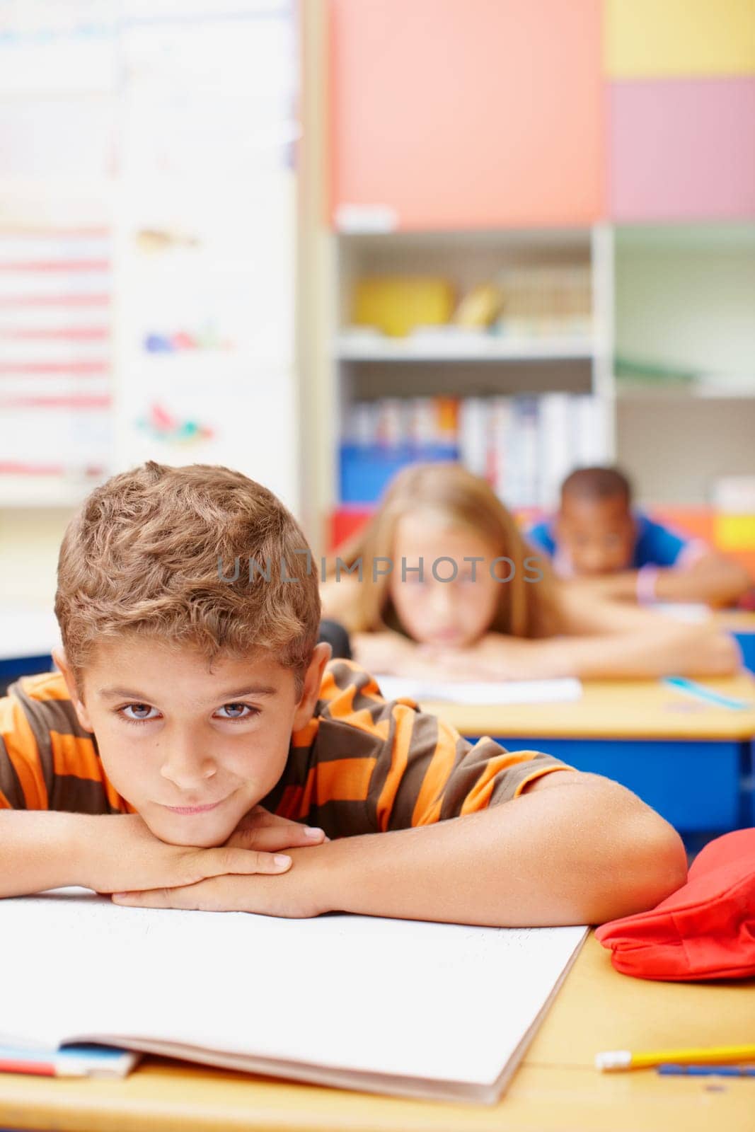 Do you have the skills to inspire these young minds - Education Training. Young boy lying on his arms looking bored with bored classmates in the background - copyspace