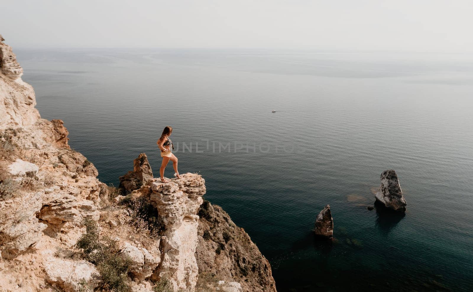 Woman travel sea. Happy tourist enjoy taking picture outdoors for memories. Woman traveler looks at the edge of the cliff on the sea bay of mountains, sharing travel adventure journey by panophotograph