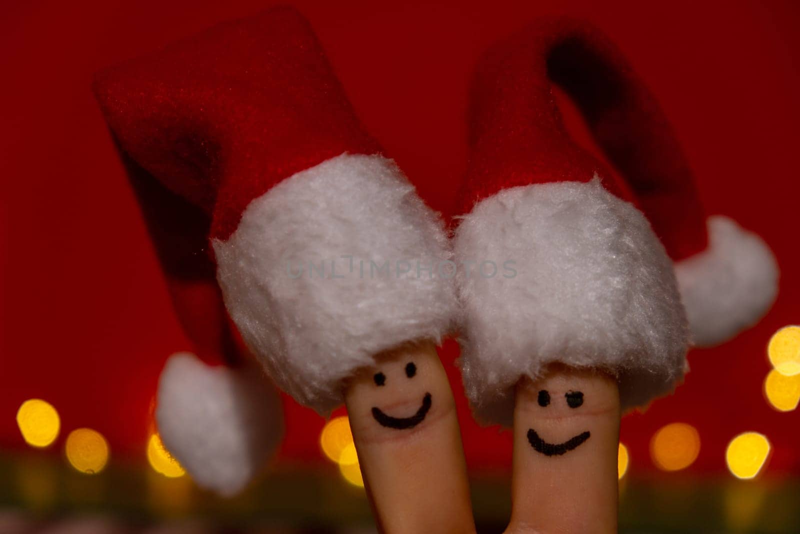 Fingers dressed in Santa-Claus red-white hats. Two happy finger smileys faces representing social network on red background. Copy space for your text Happy family celebrating concept for Christmas or New Years day. Finger couple by anna_stasiia
