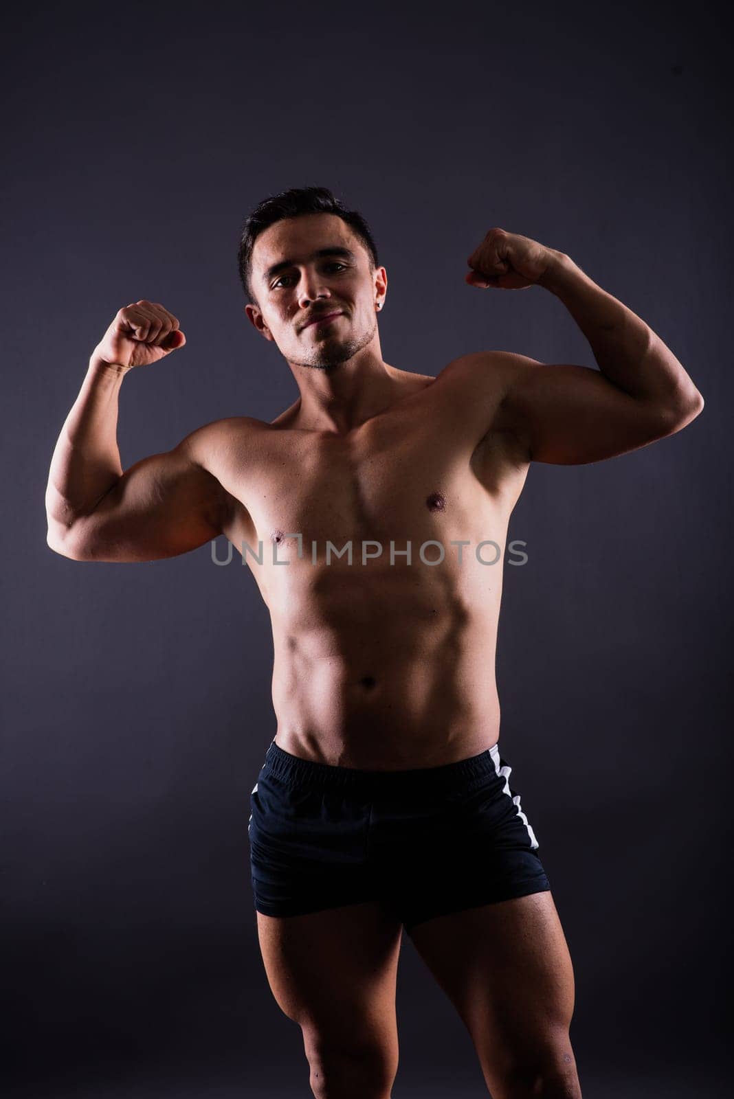 Handsome muscular shirtless young man standing confident, front view, looking at camera by Zelenin