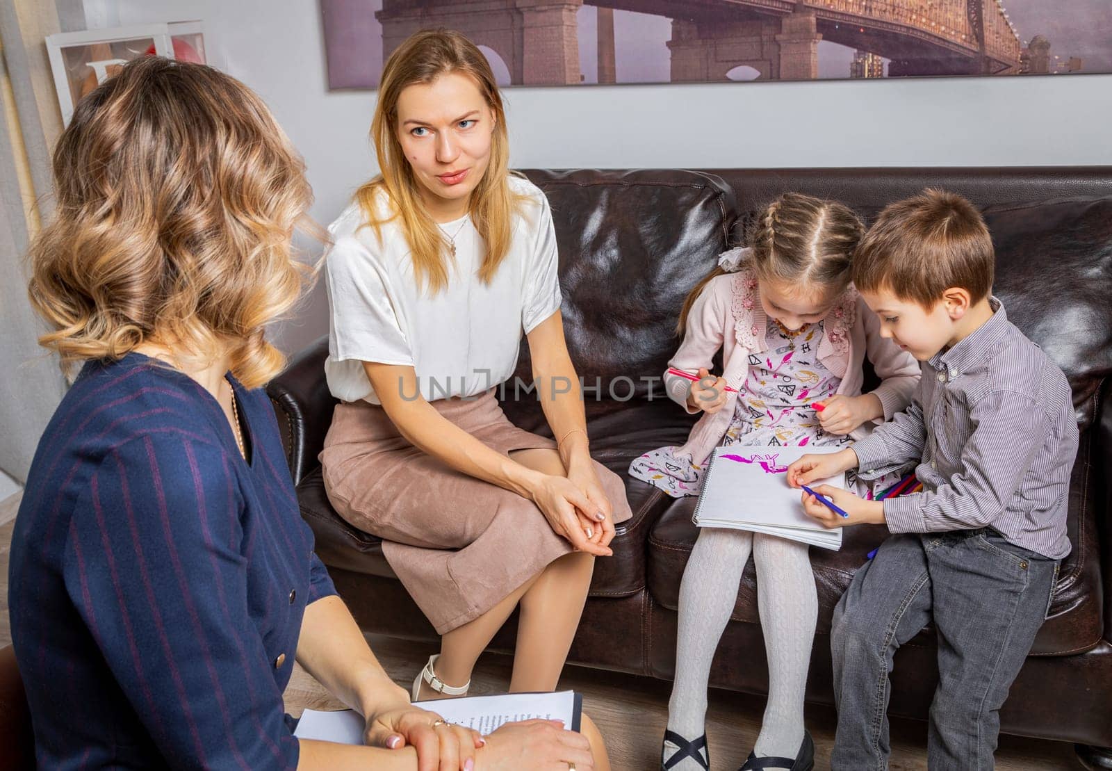 Mother with children at the reception of a psychologist, asking for advice on how to communicate with the children. by Yurich32