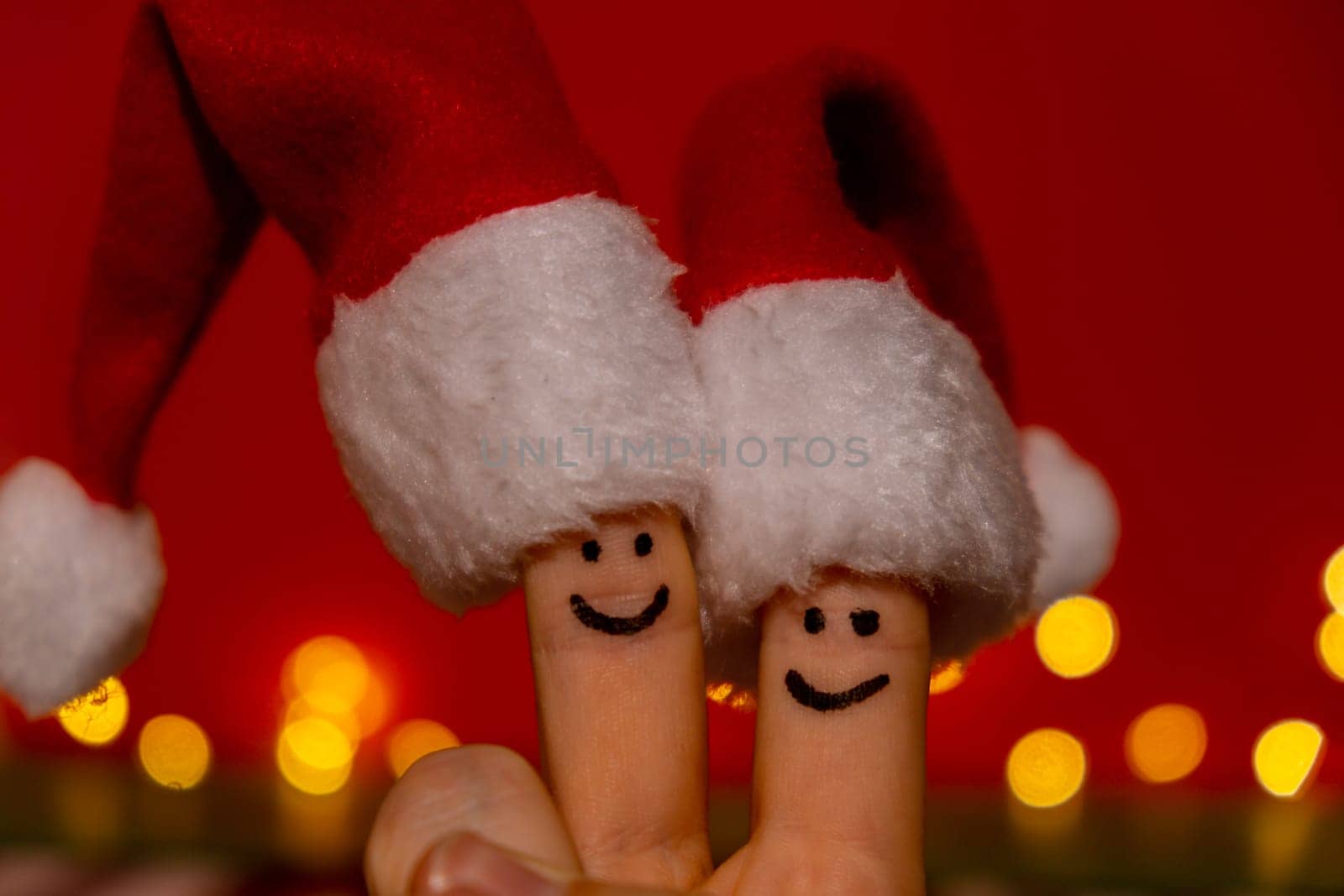 Fingers dressed in Santa-Claus red-white hats. Two happy finger smileys faces representing social network on red background. Copy space for your text Happy family celebrating concept for Christmas or New Years day. Finger couple by anna_stasiia