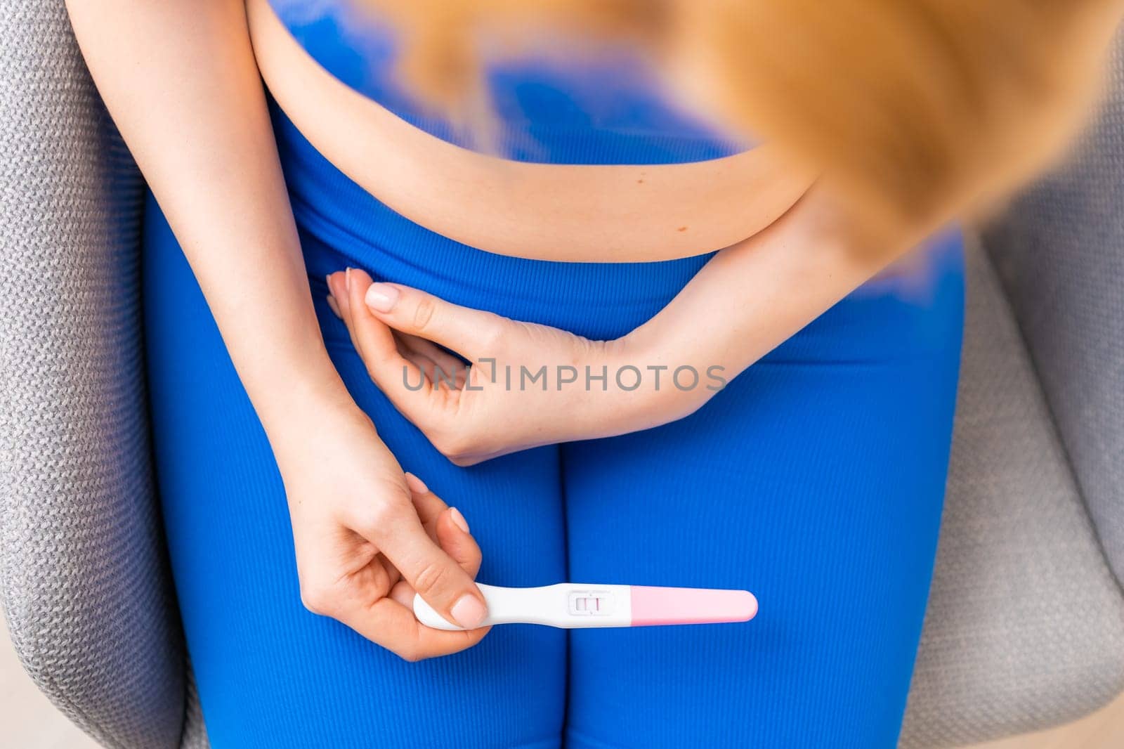 Top view on the woman holding a pregnancy test in her hands.