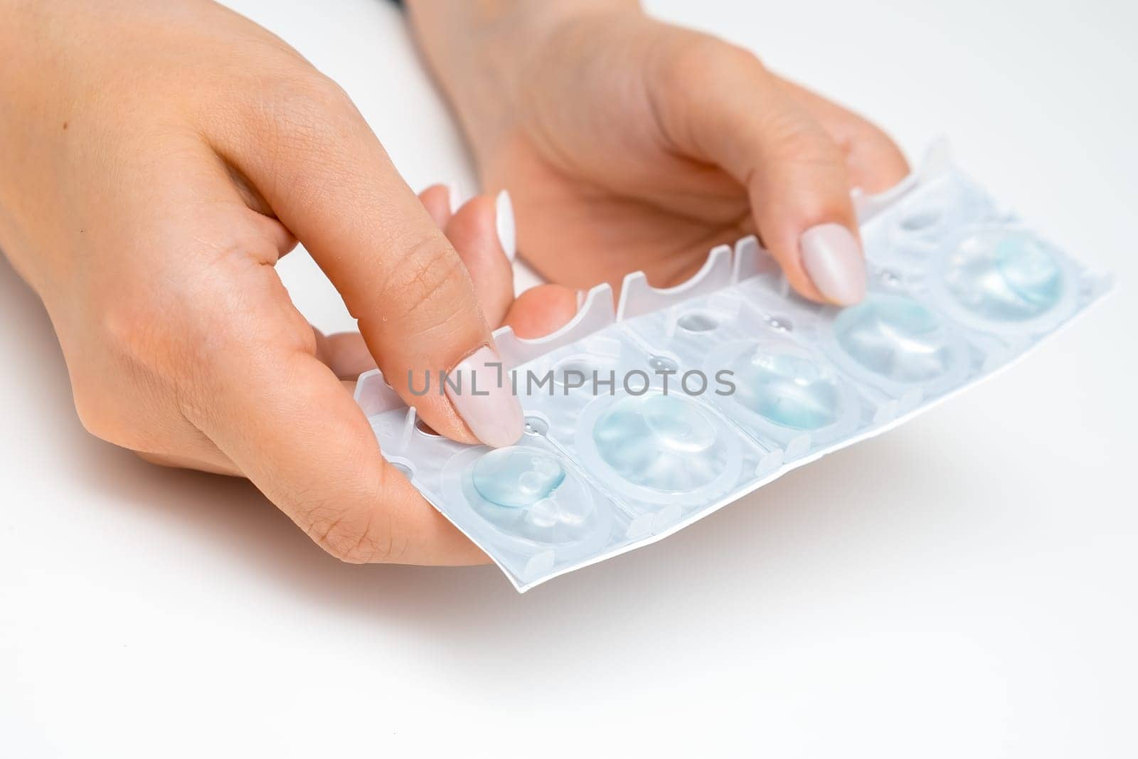 Close up womans hands holding contact lenses in her hands on the white background.