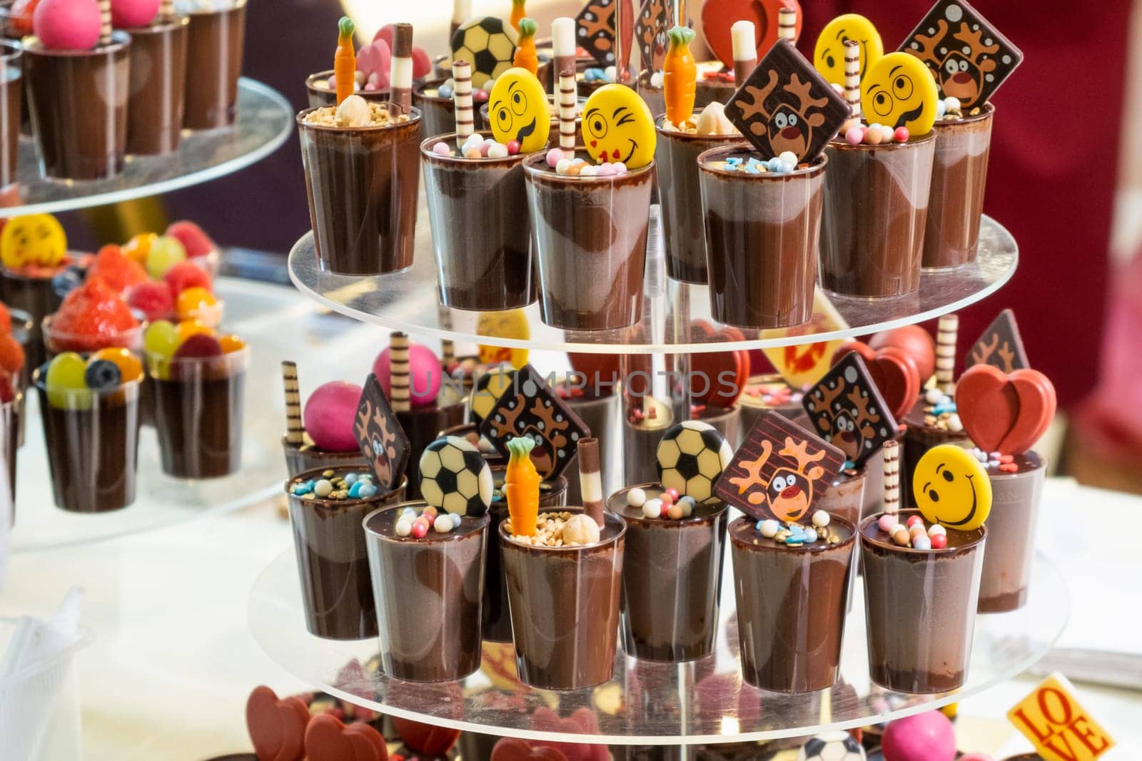 Chocolate dessert with cream decorated with football balls and smiles in the form of pyramid. Concept of candy bar for birthday party.