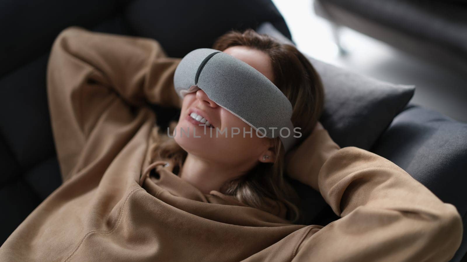 Woman with eye massage device lying on sofa. Treatment of myopia and tired eyes at home concept