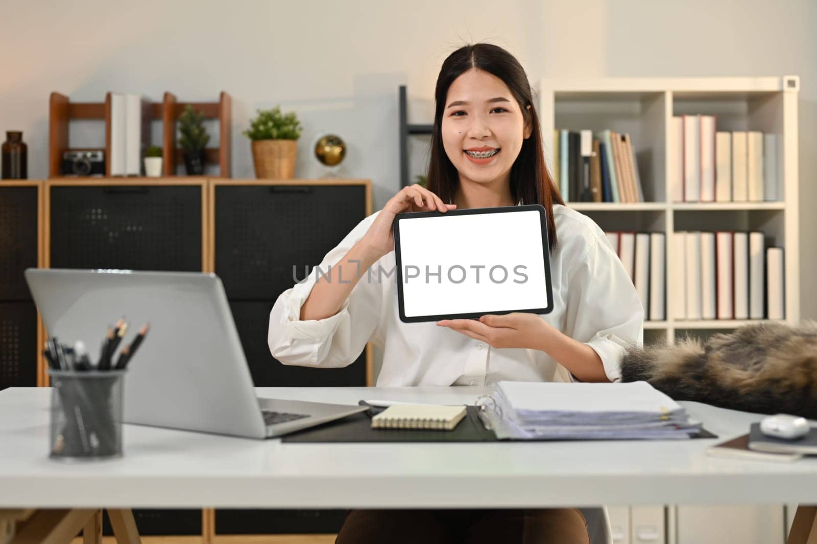 Confident asian female entrepreneur showing digital tablet and smiling to camera. Blank screen for your advertising text message.