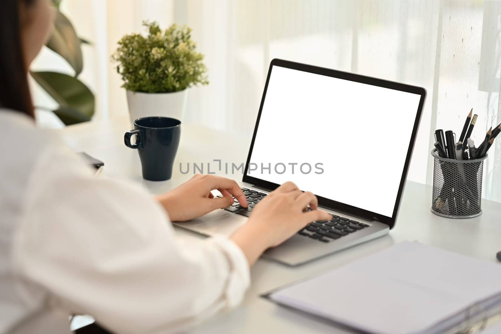 Businesswoman shoulder hand typing on keyboard of laptop computer. White screen for graphic display montage.