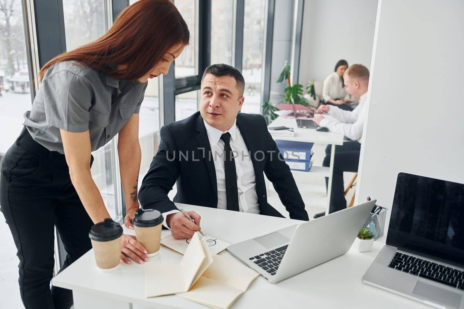 Works by using laptop. Group of people in official formal clothes that is indoors in the office.