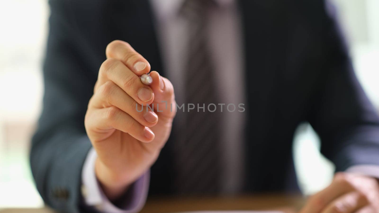 Businessman in suit holding ballpoint pen in hand closeup. Business administration concept