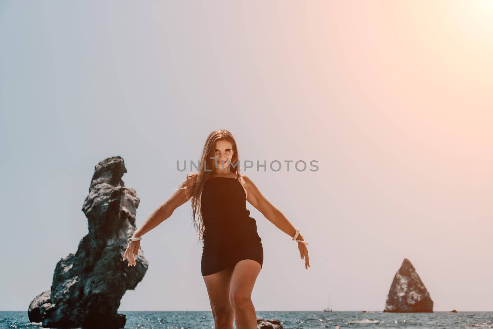 Woman summer travel sea. Happy tourist in hat enjoy taking picture outdoors for memories. Woman traveler posing on the beach at sea surrounded by volcanic mountains, sharing travel adventure journey by panophotograph