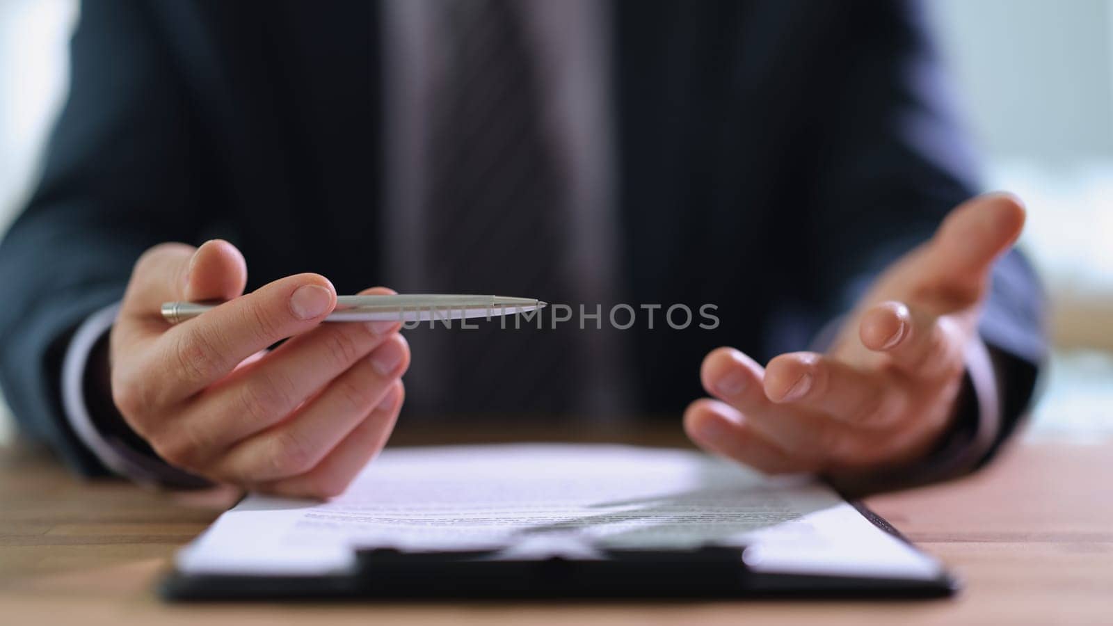 Businessman in suit holding metal ballpoint pen in hands and talking to client in office closeup. Financial economic deals in business concept