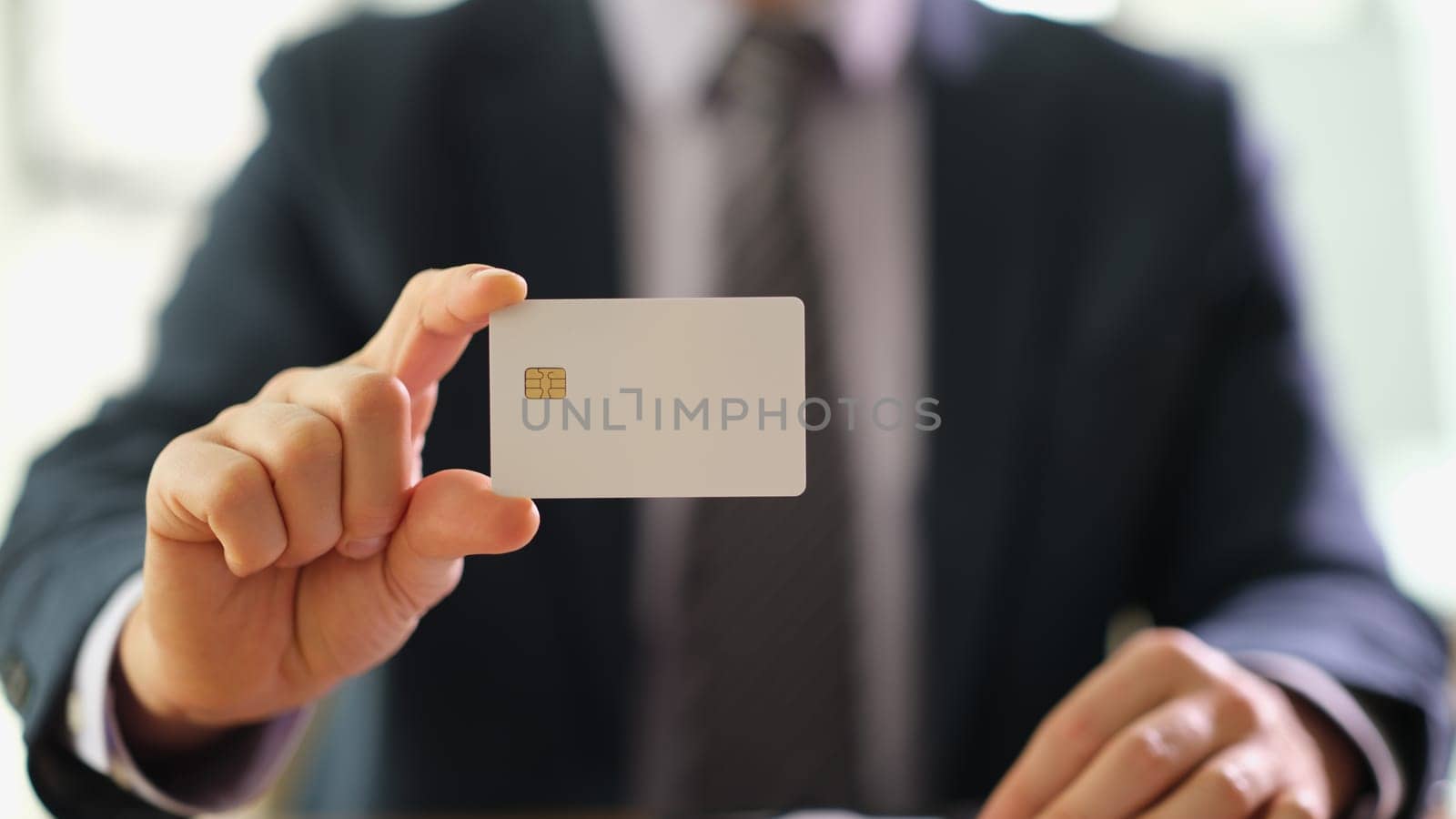 Businessman holding plastic credit bank card in hands at work in office closeup. Financial transactions concept