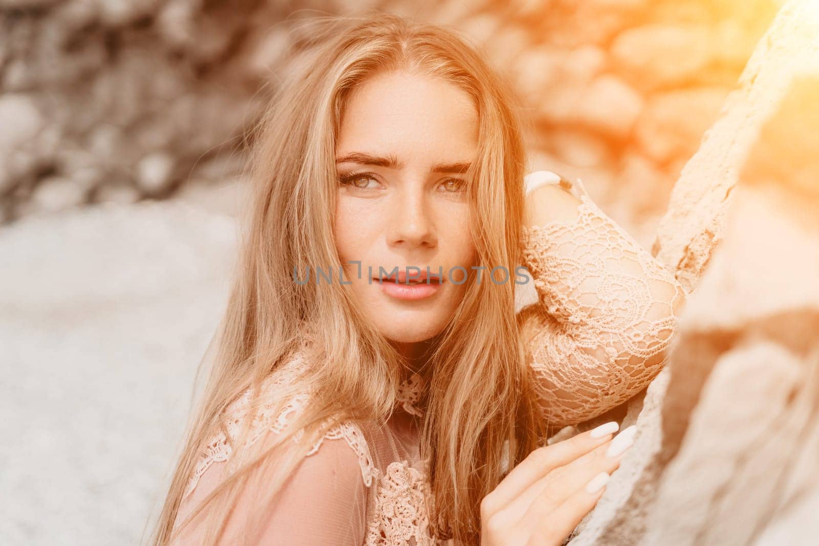 Woman summer travel sea. Happy tourist in beige dress enjoy taking picture outdoors for memories. Woman traveler posing on the beach surrounded by volcanic mountains, sharing travel adventure journey by panophotograph