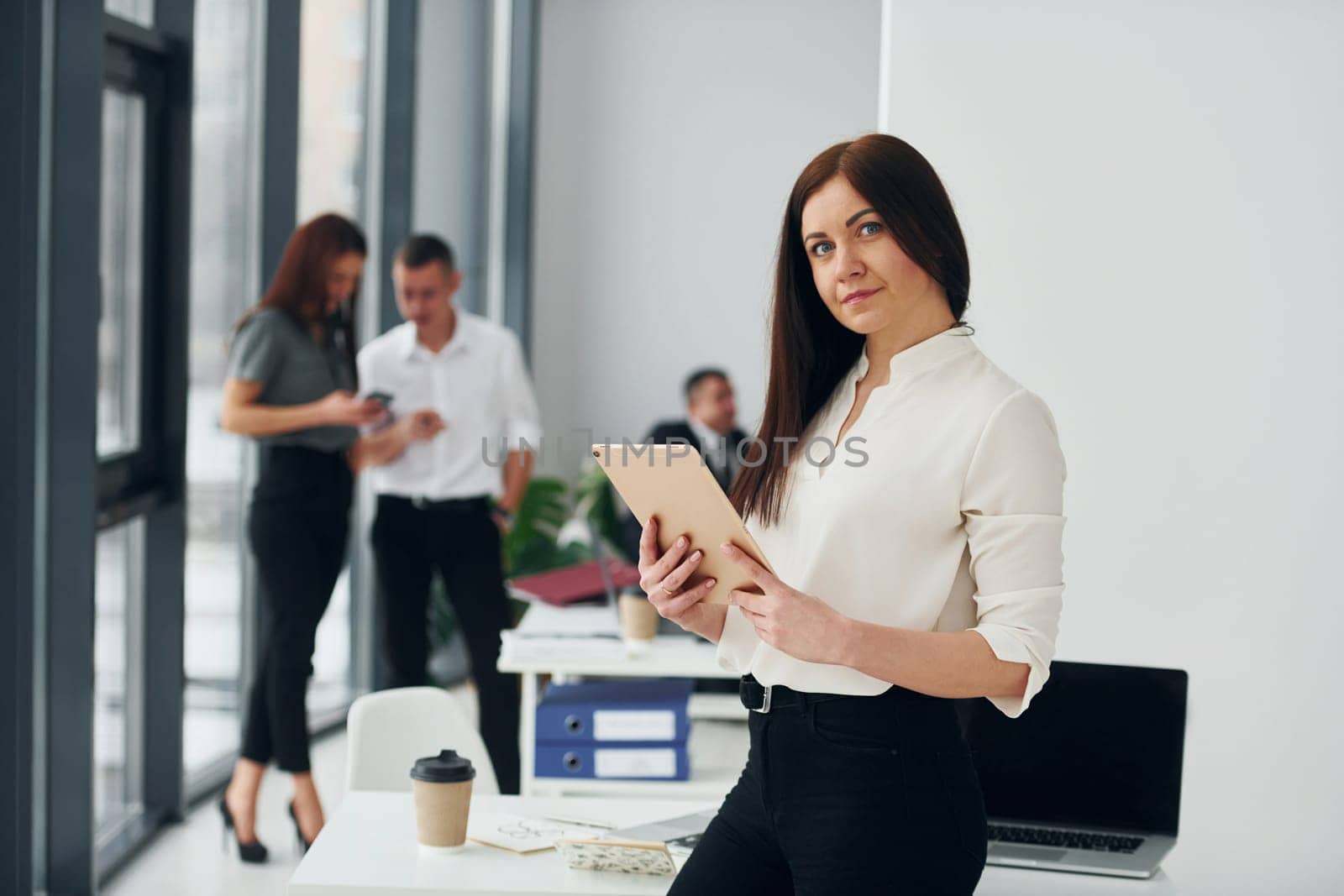 Woman in front of her colleagues. Group of people in official formal clothes that is indoors in the office by Standret