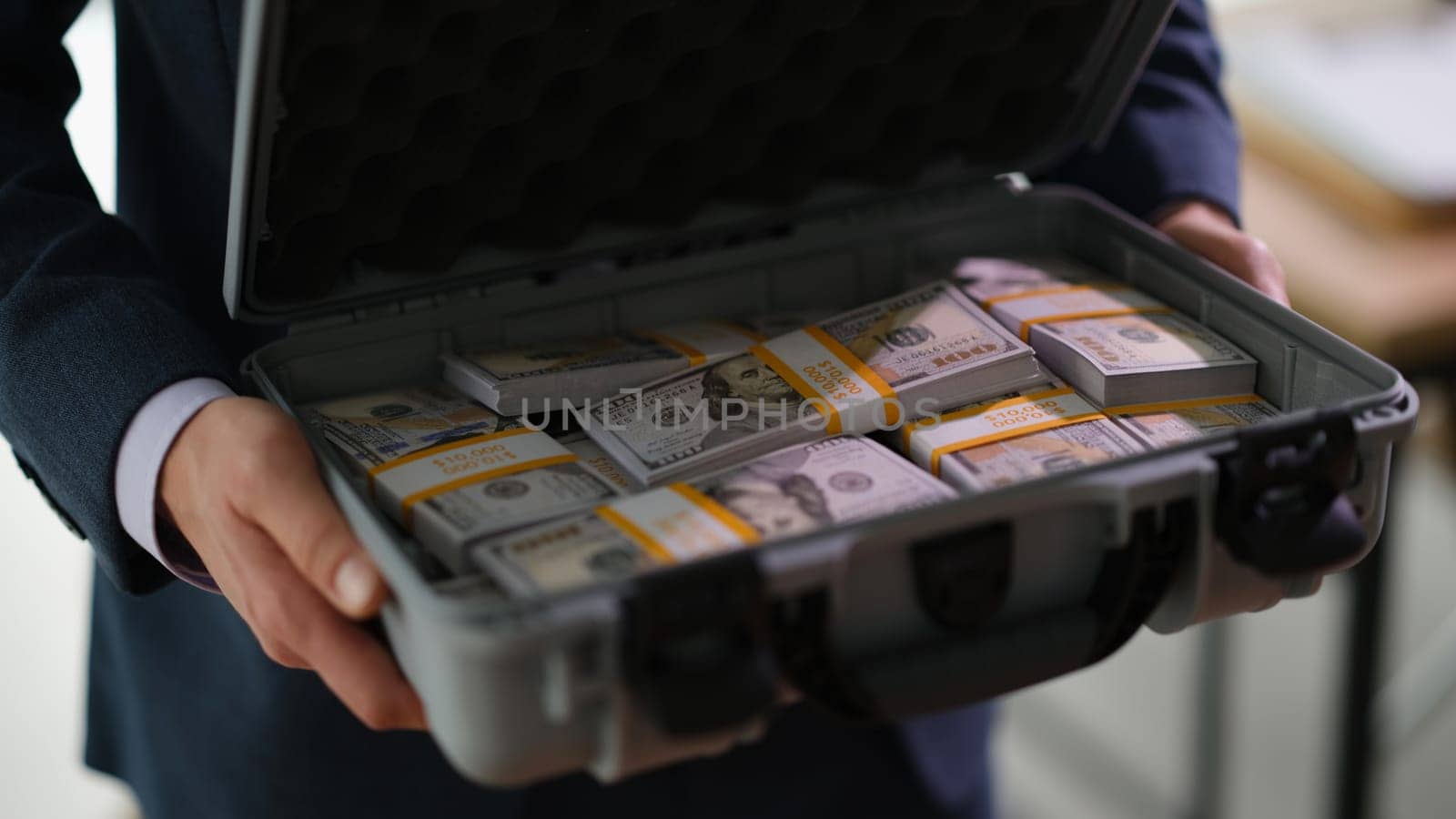 Businessman holding suitcase full of dollar bills closeup. Bribe on large scale concept