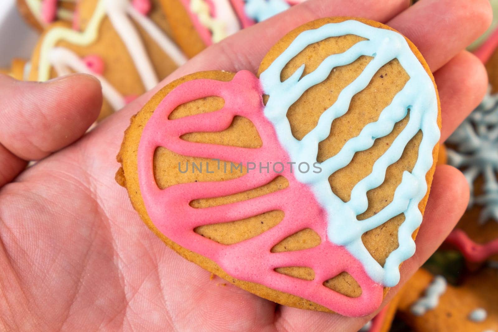 Man holding a heart shaped sugar cookies for St Valentines Day with colorful icing by vladimka