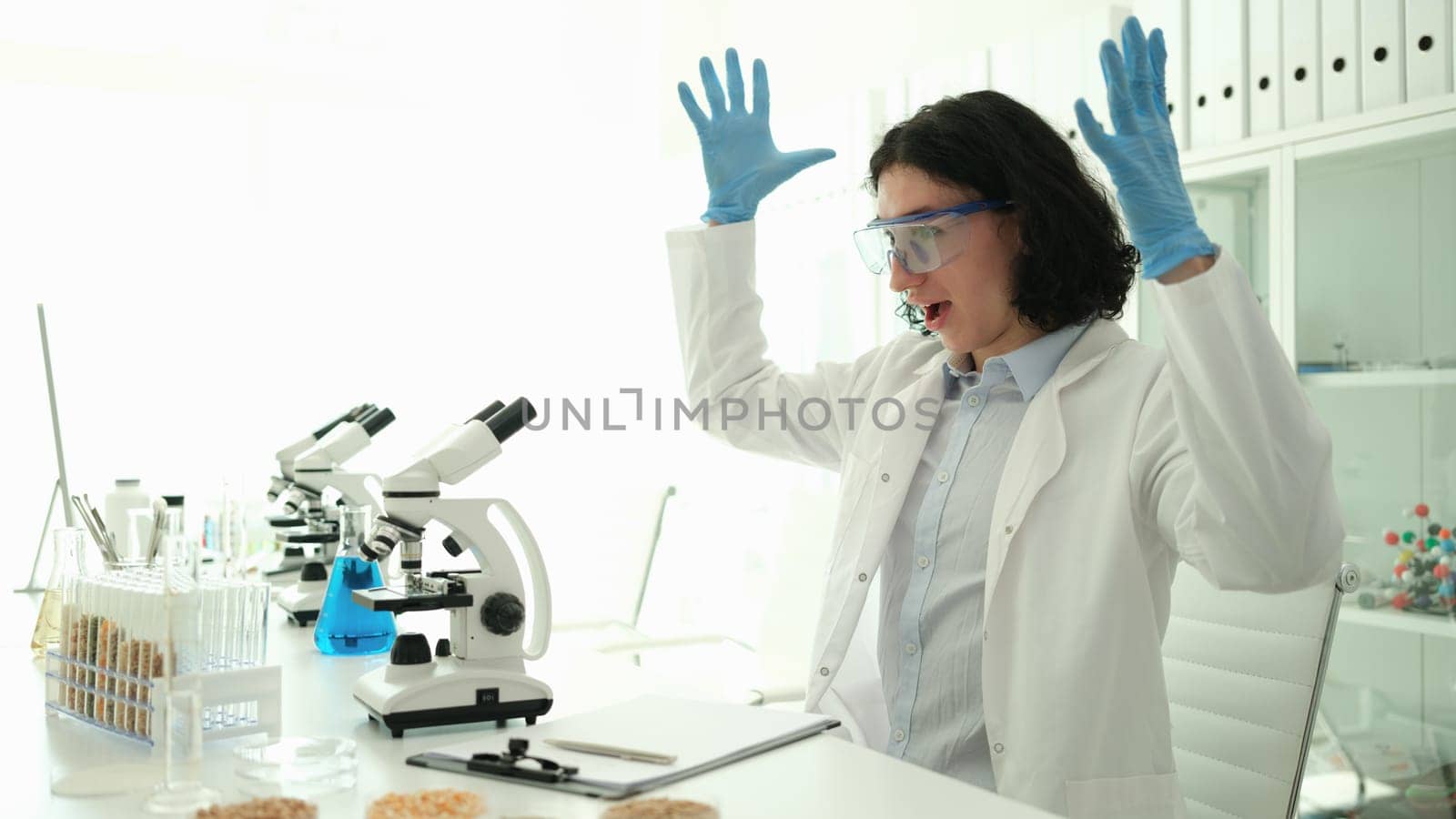 Scientist chemist rejoicing and raising hands up because of new invention in chemical laboratory. Successful chemical experiments and discoveries concept