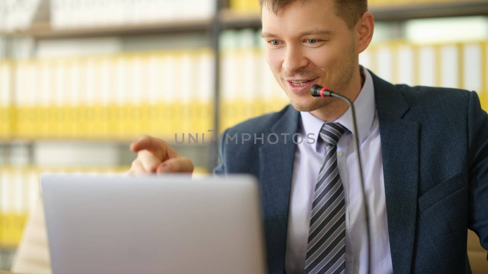 Businessman coach speaking into microphone in front of laptop in office. Business education concept