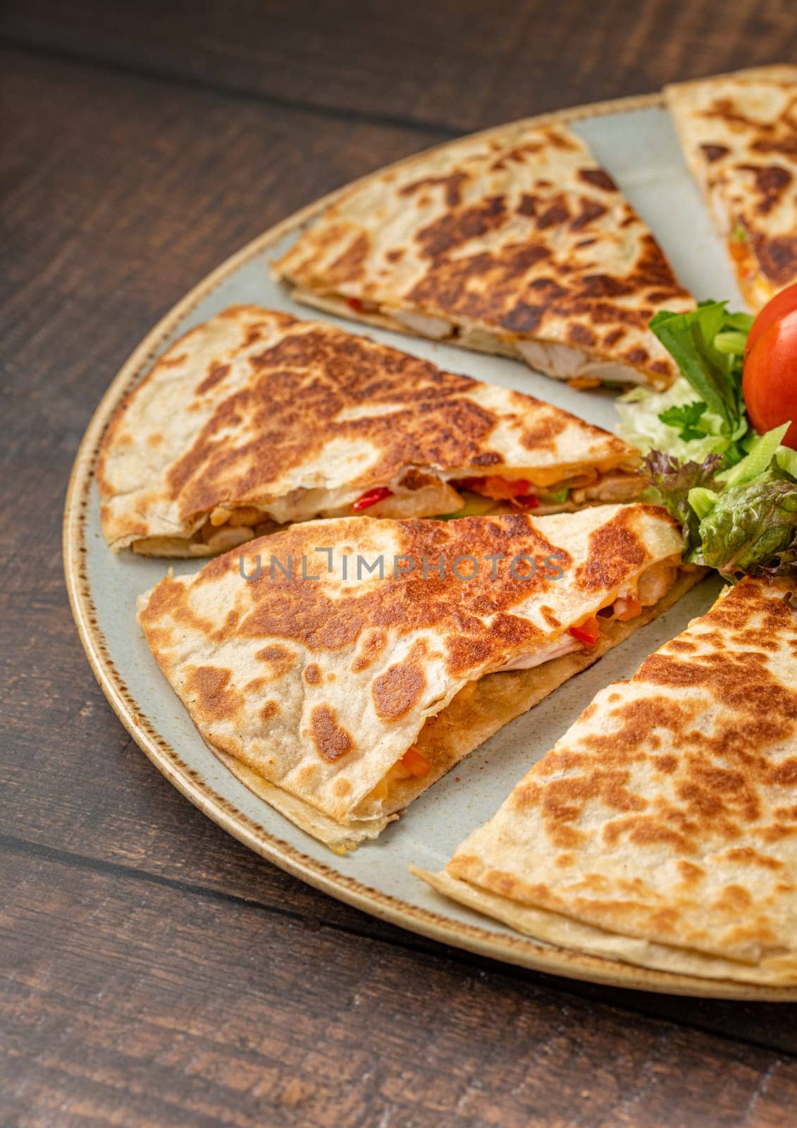 Mexican quesadilla with chicken, cheese and peppers on wooden table by Sonat