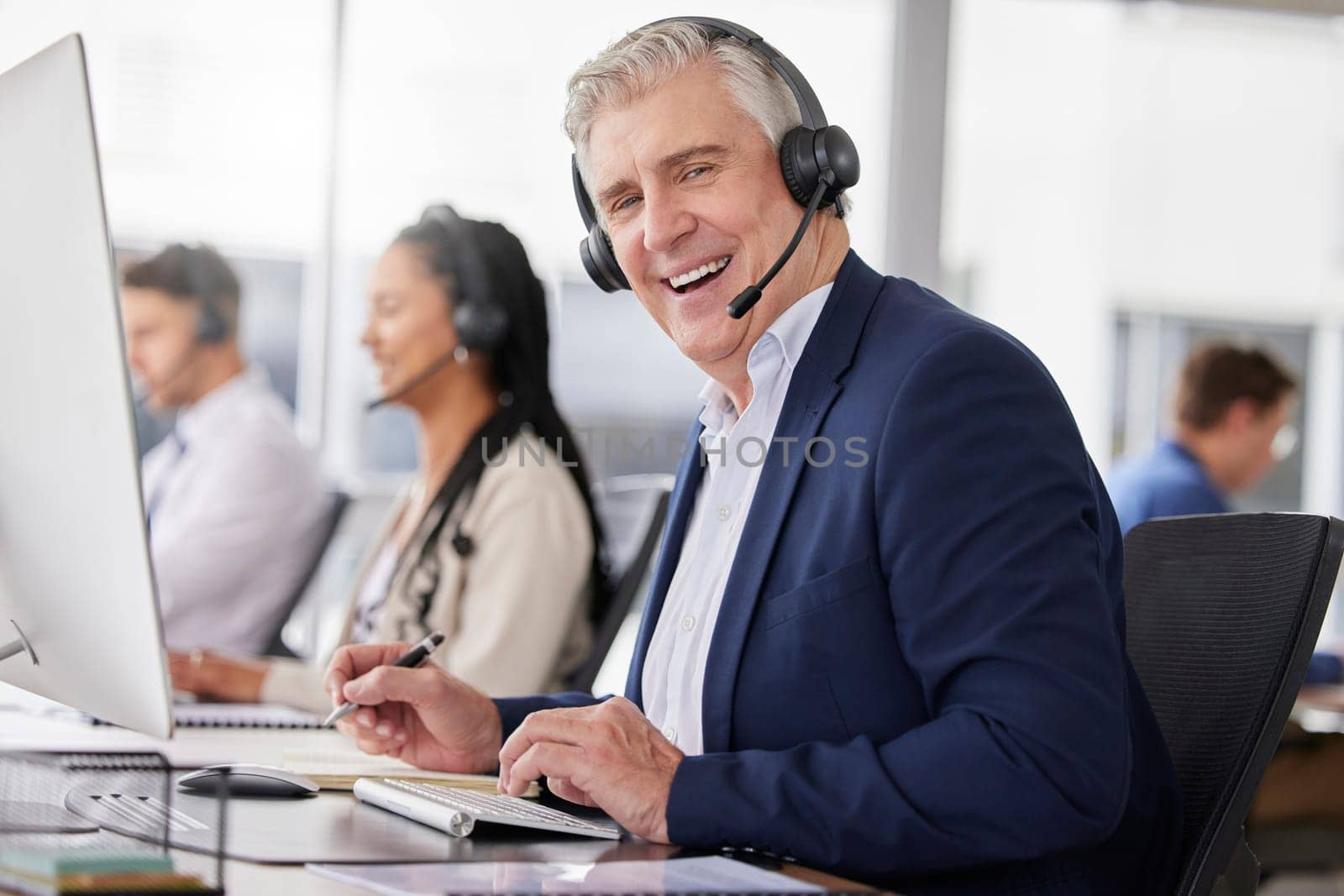 Portrait, laughing and man in call center in office working on customer service in workplace. Telemarketing, mature person and funny sales agent, consultant and telemarketer writing information. by YuriArcurs