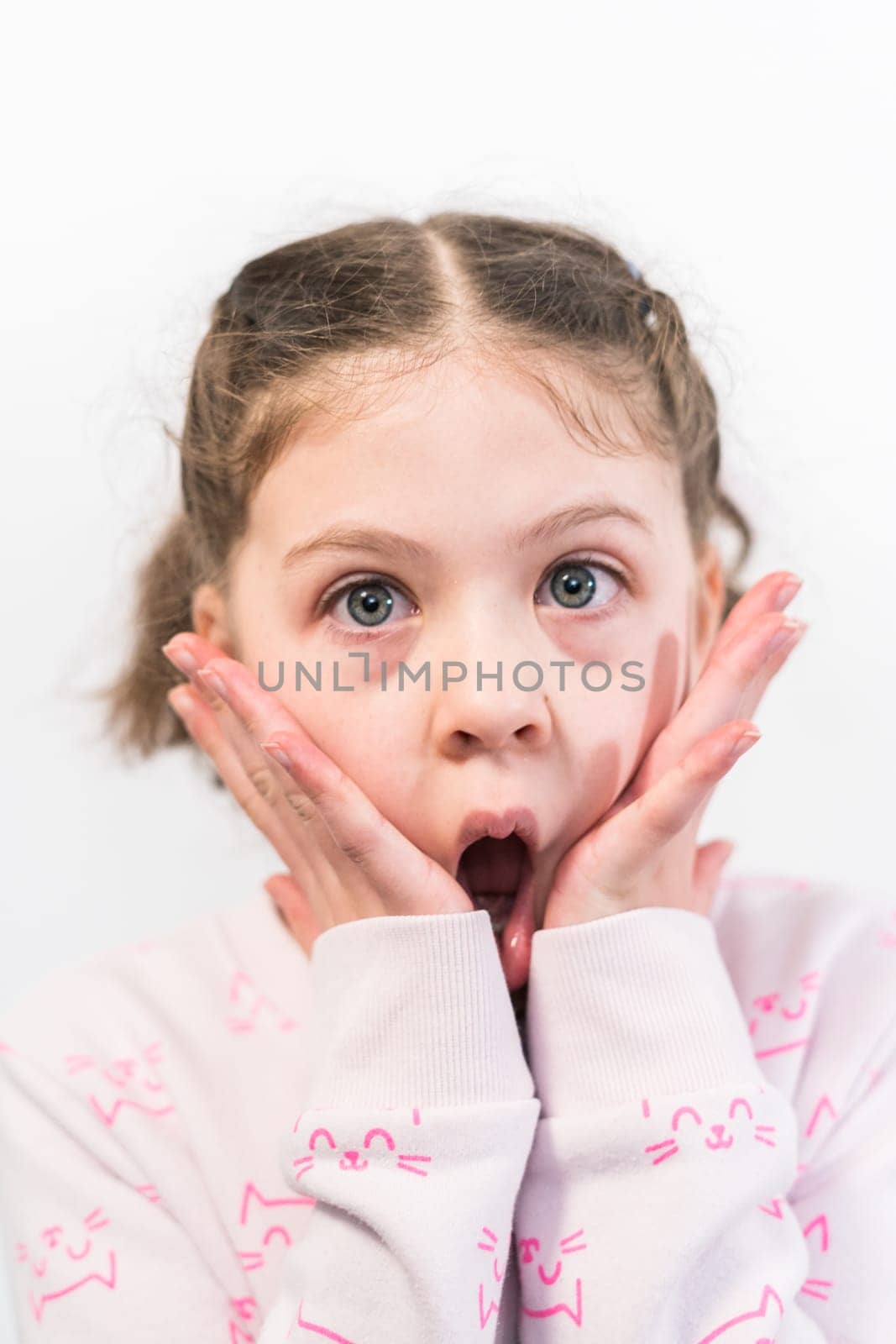 Little girl with rainbow braces with a surprised face.