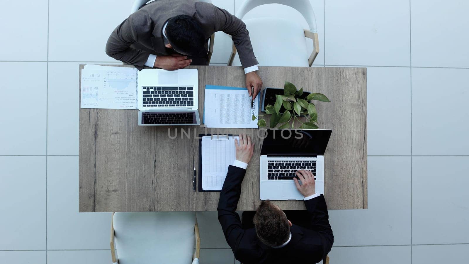Two successful smiling businessmen are working on a laptop. view from above by Prosto