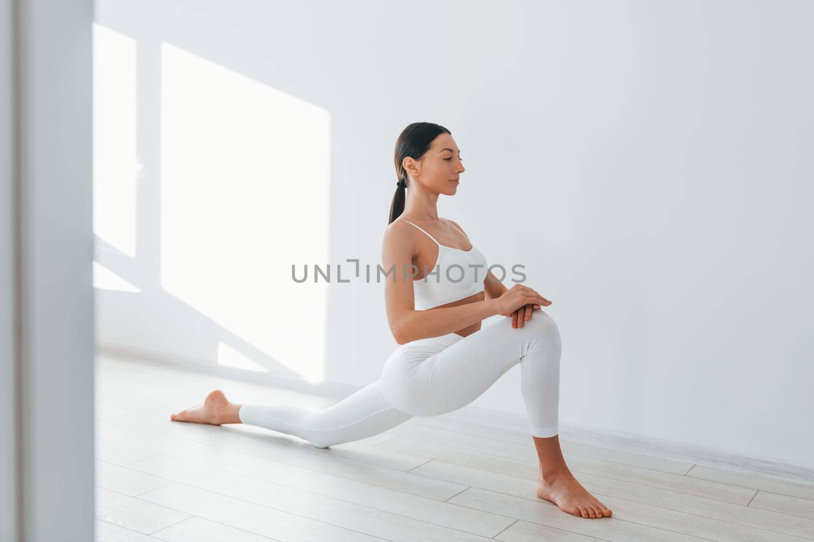 Doing yoga. Young caucasian woman with slim body shape is indoors at daytime.