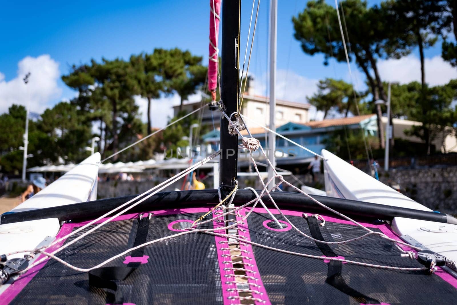 Boat deck on sea beach closeup. Pink ship on seacoast with view on holiday houses