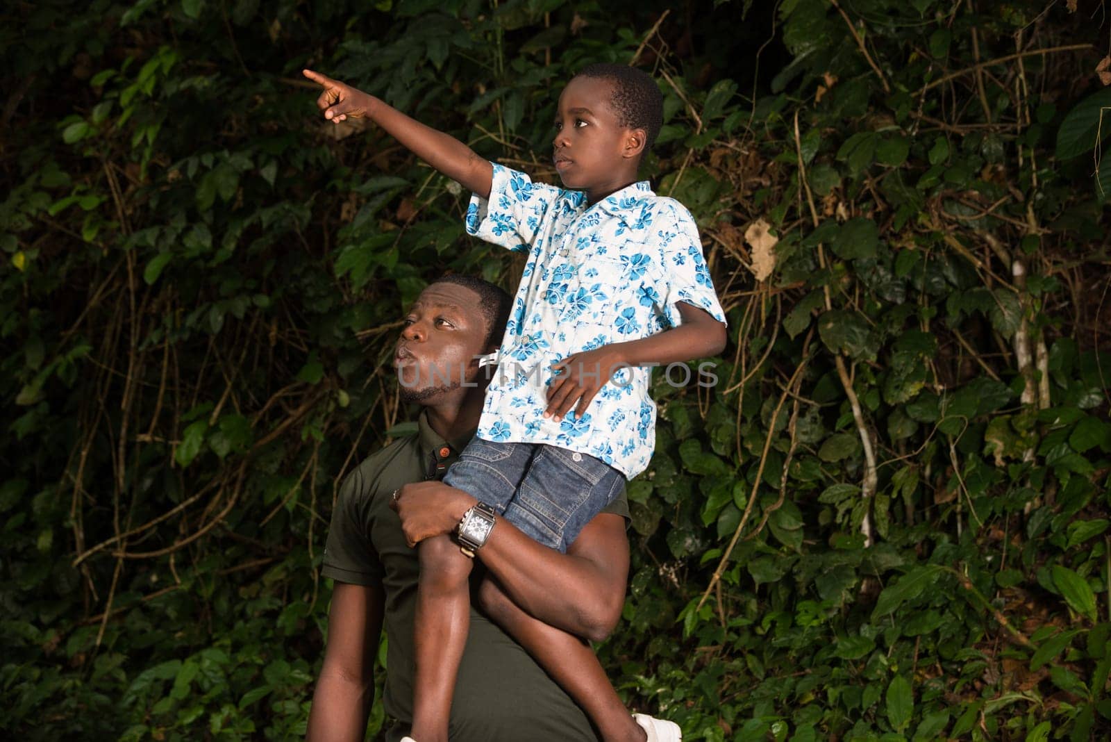 a young boy on the shoulder of his father showing him something up there.