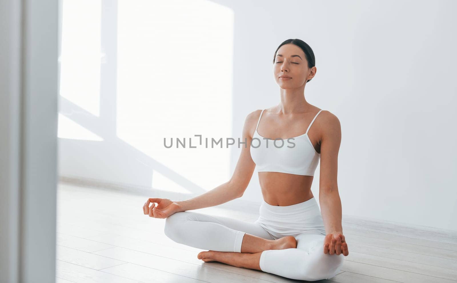 Doing yoga. Young caucasian woman with slim body shape is indoors at daytime by Standret