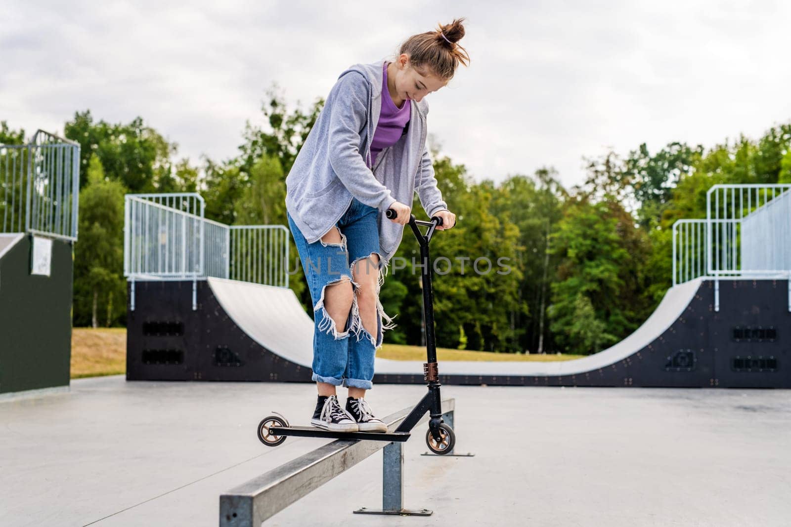 Pretty girl with scooter on ramp making extreme. Cute teenager posing with eco vehicle outdoors