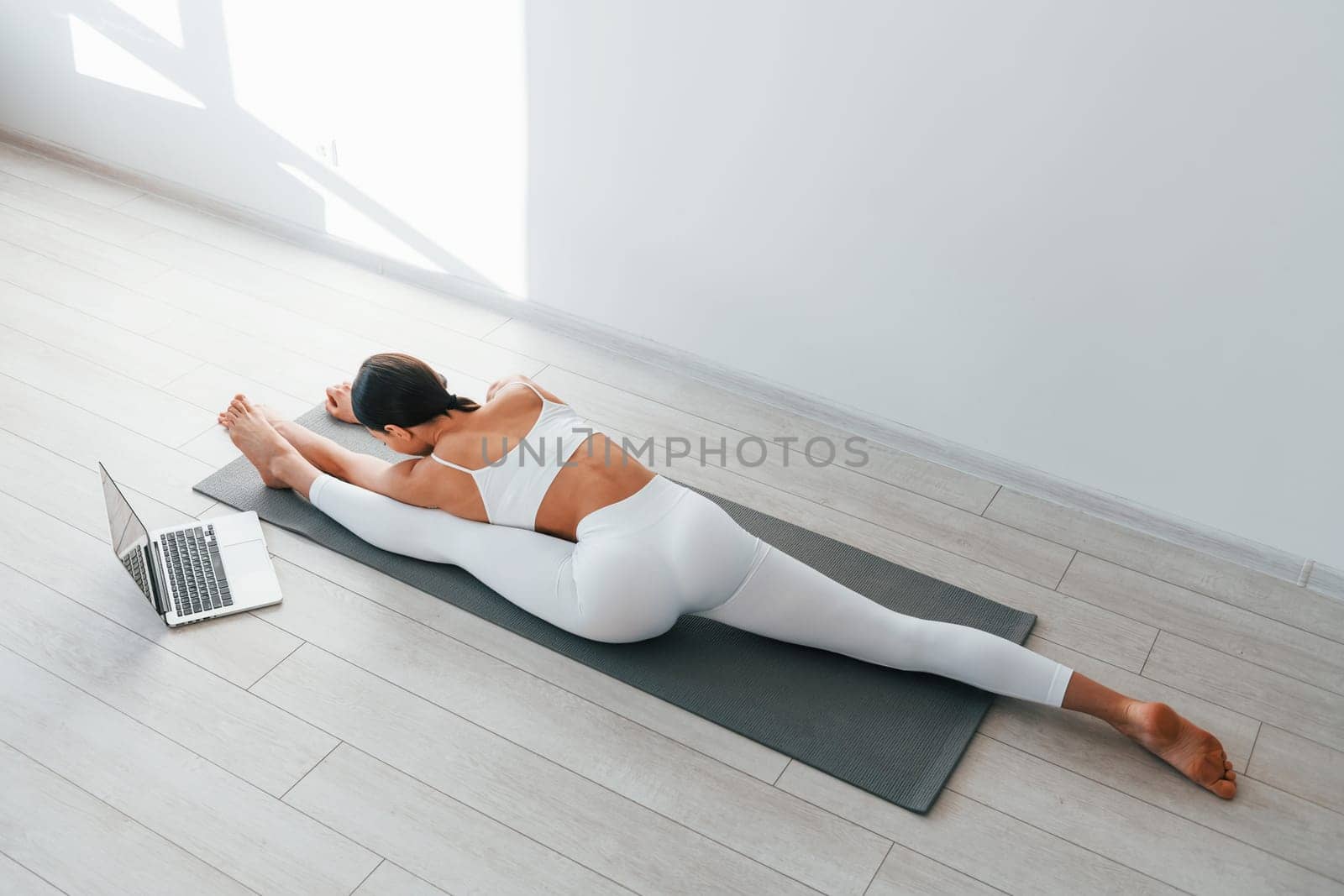 With laptop. Young caucasian woman with slim body shape is indoors at daytime by Standret