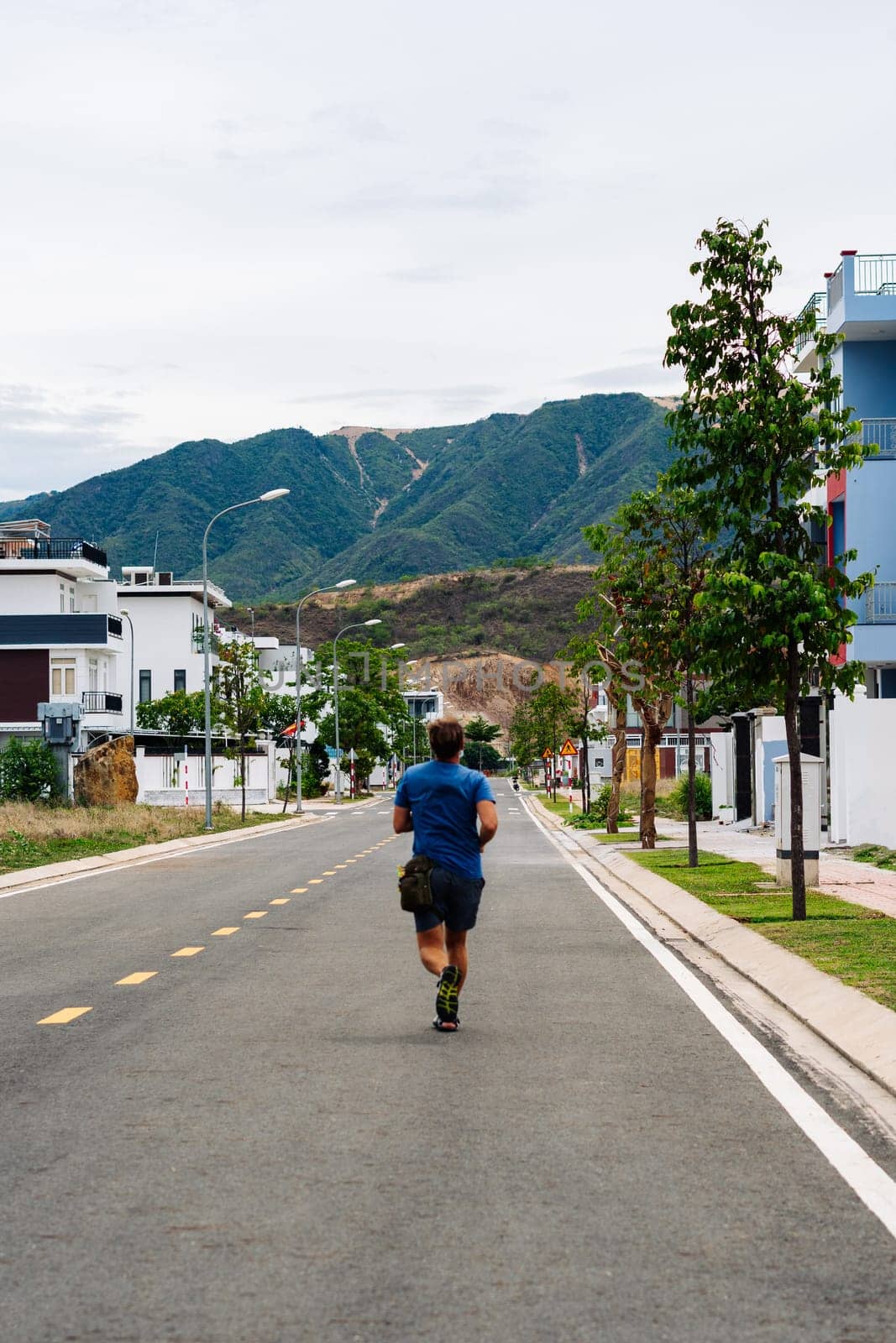 A man runs down a road in the city mountain VERTICAL FORMAT BACK VIEW.