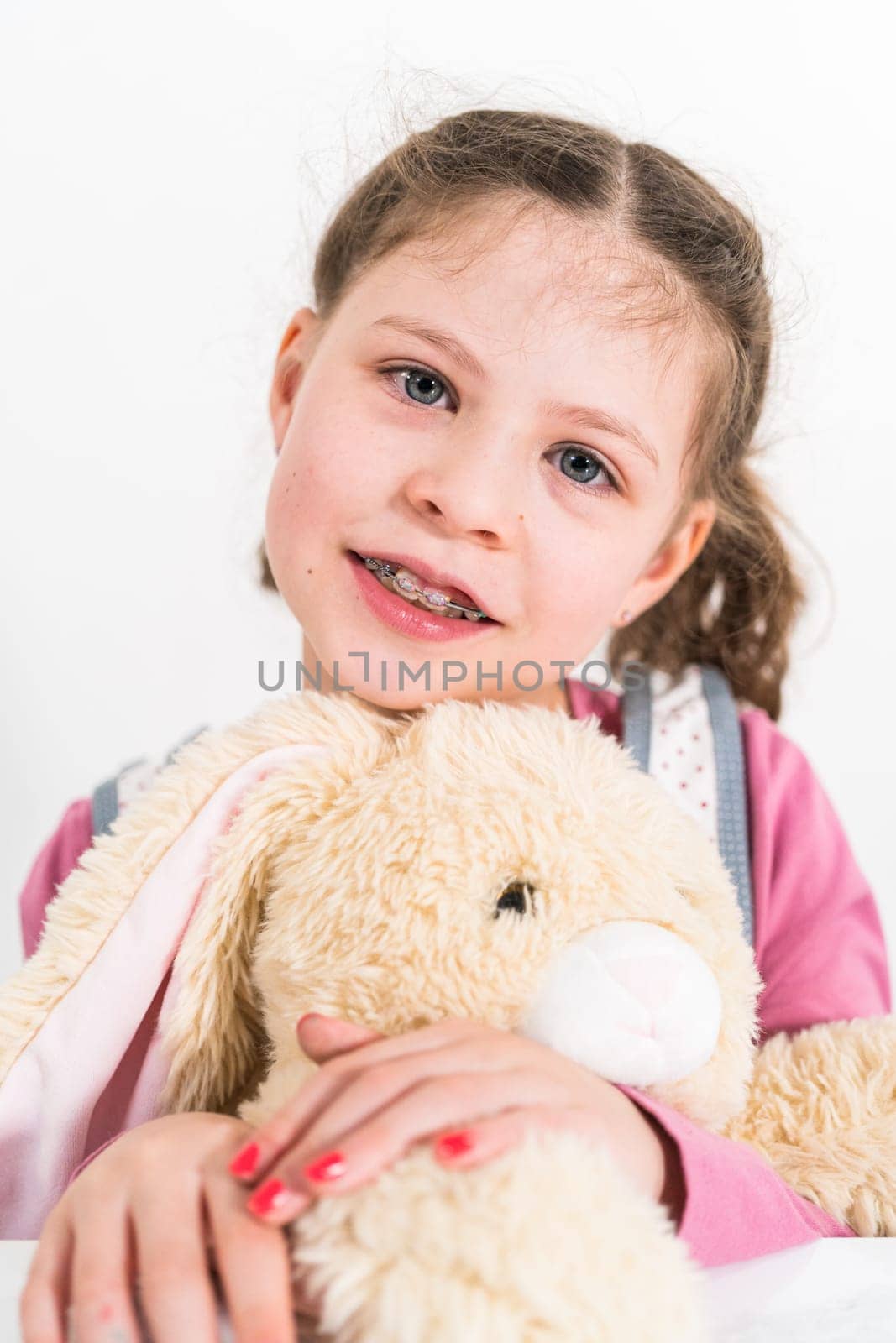 Easter egg coloring. Little girl hugging her big stuffed bunny.