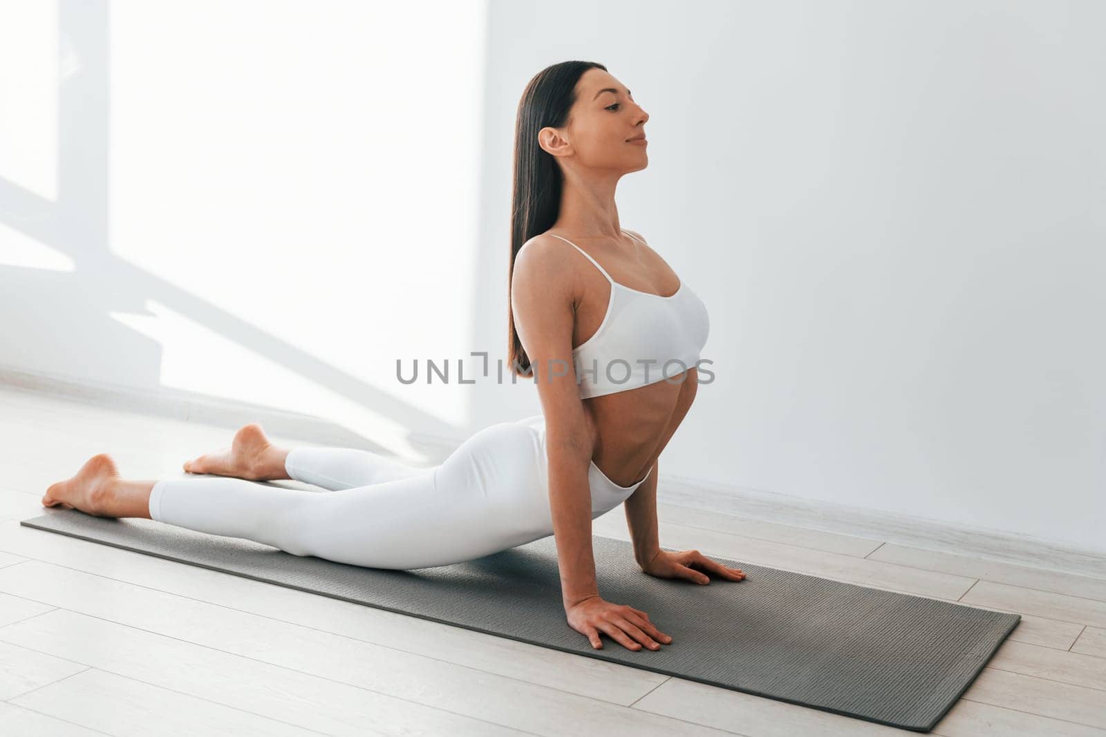 Doing exercises. Young caucasian woman with slim body shape is indoors at daytime.