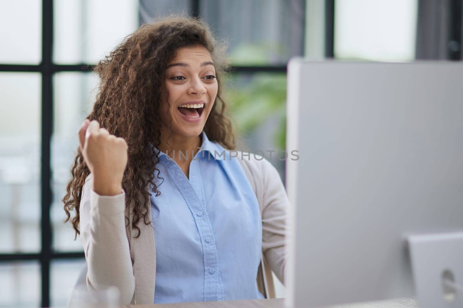 expressive young woman open mouth checking discounts for online shopping sitting at desktop .