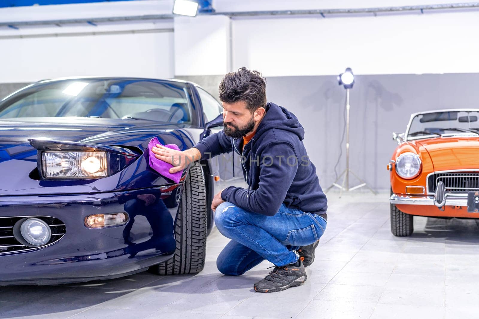 detailing and polishing the body of a luxury sports car using a microwipe. High quality photo