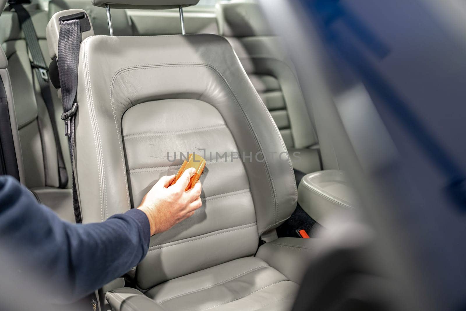 cleaning leather car seats with a brush and chemicals.