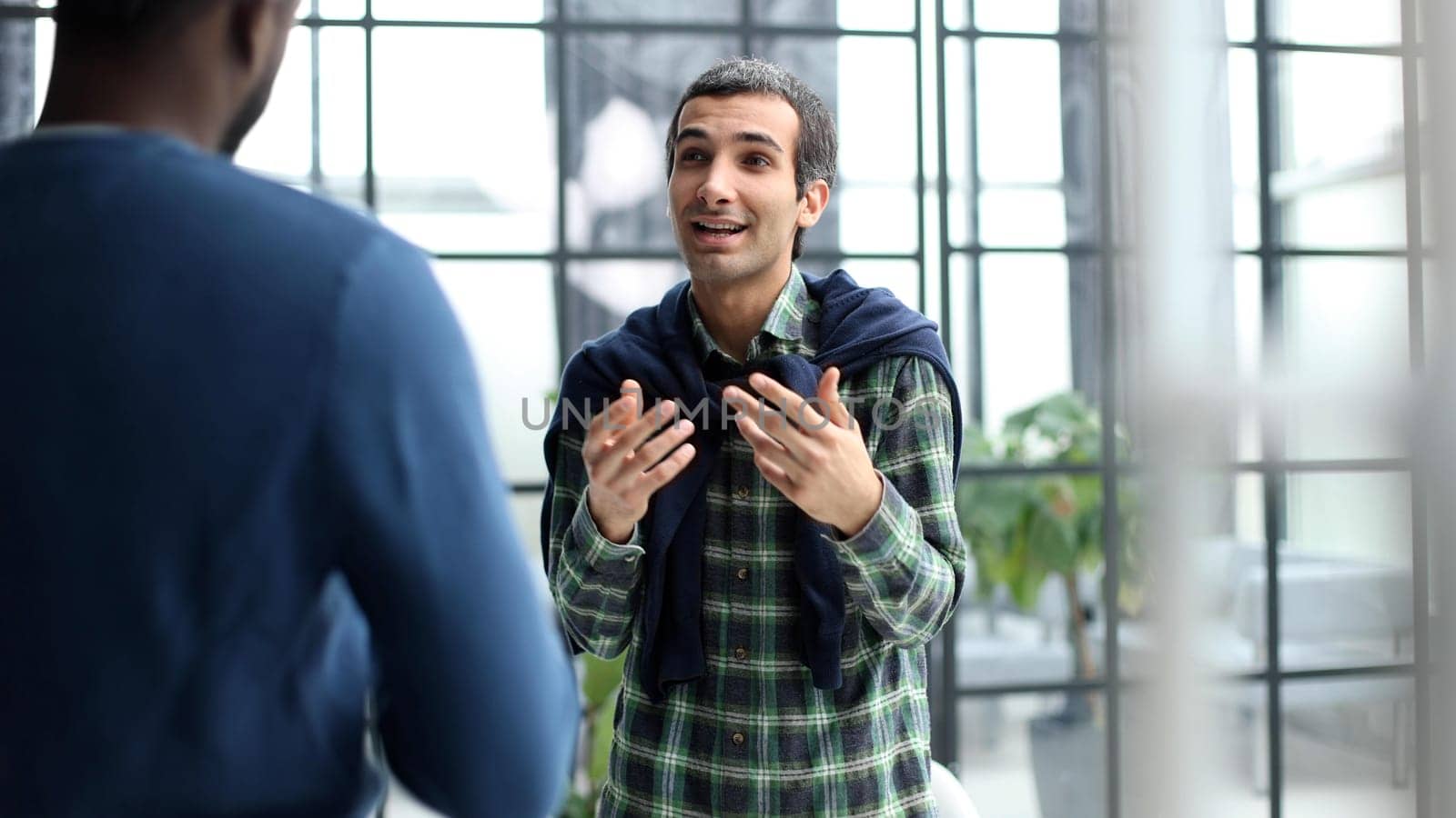 Diverse male colleagues in modern office corridor, young african american and caucasian business people discussing common project work, meeting in company work