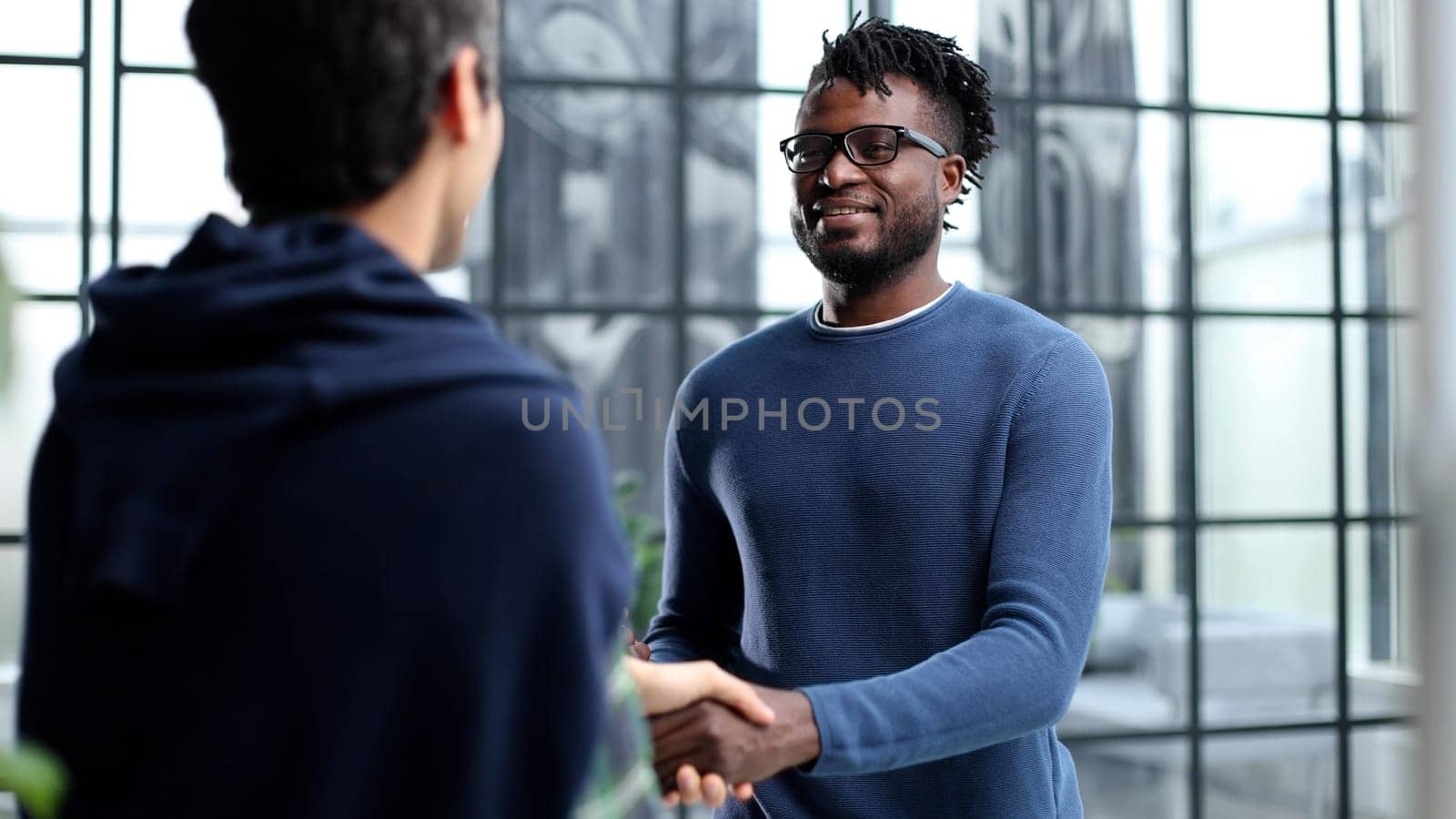 Diverse male colleagues in modern office corridor, young african american and caucasian business people discussing common project work, meeting in company work