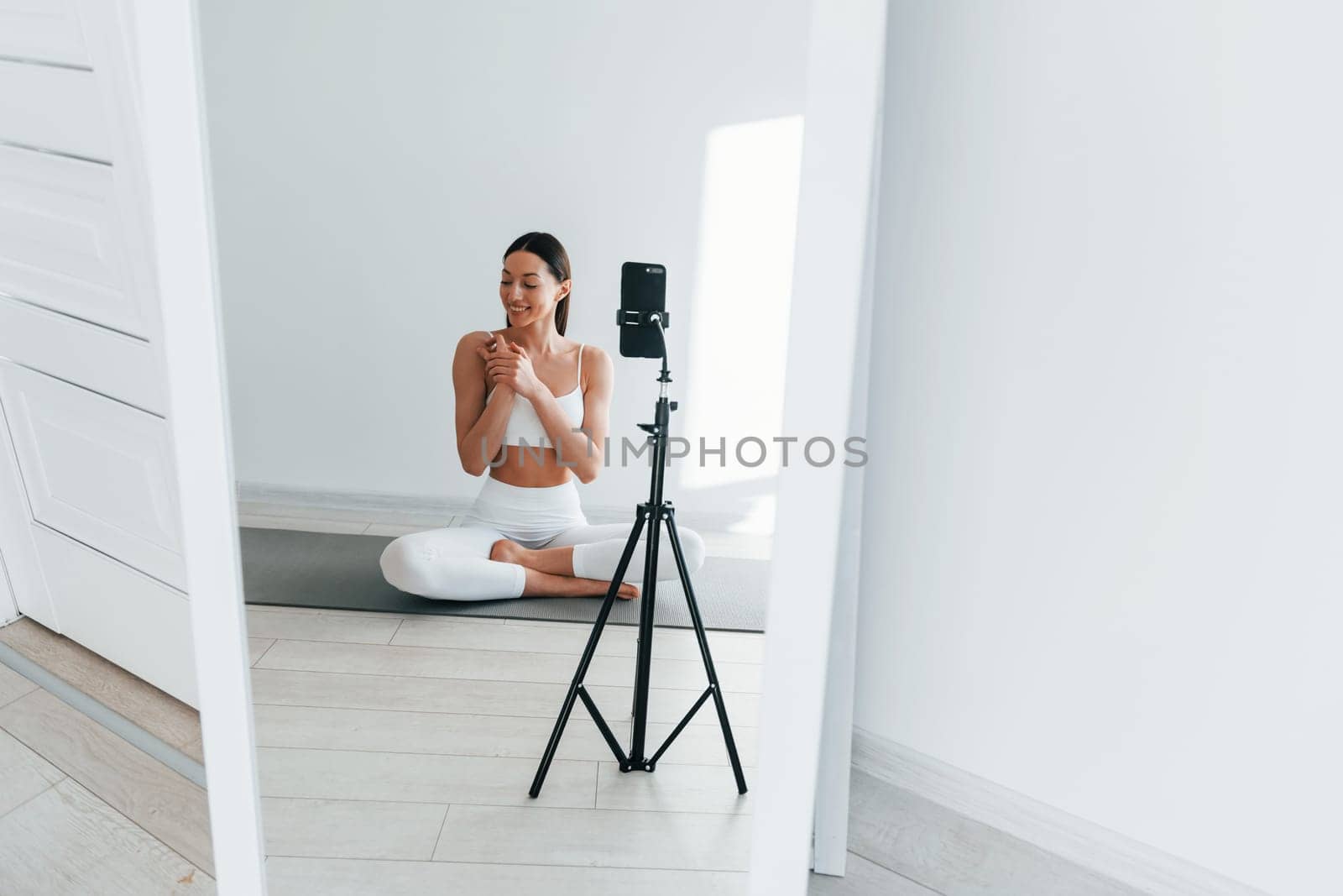 Phone is recording video. Young caucasian woman with slim body shape is indoors at daytime.