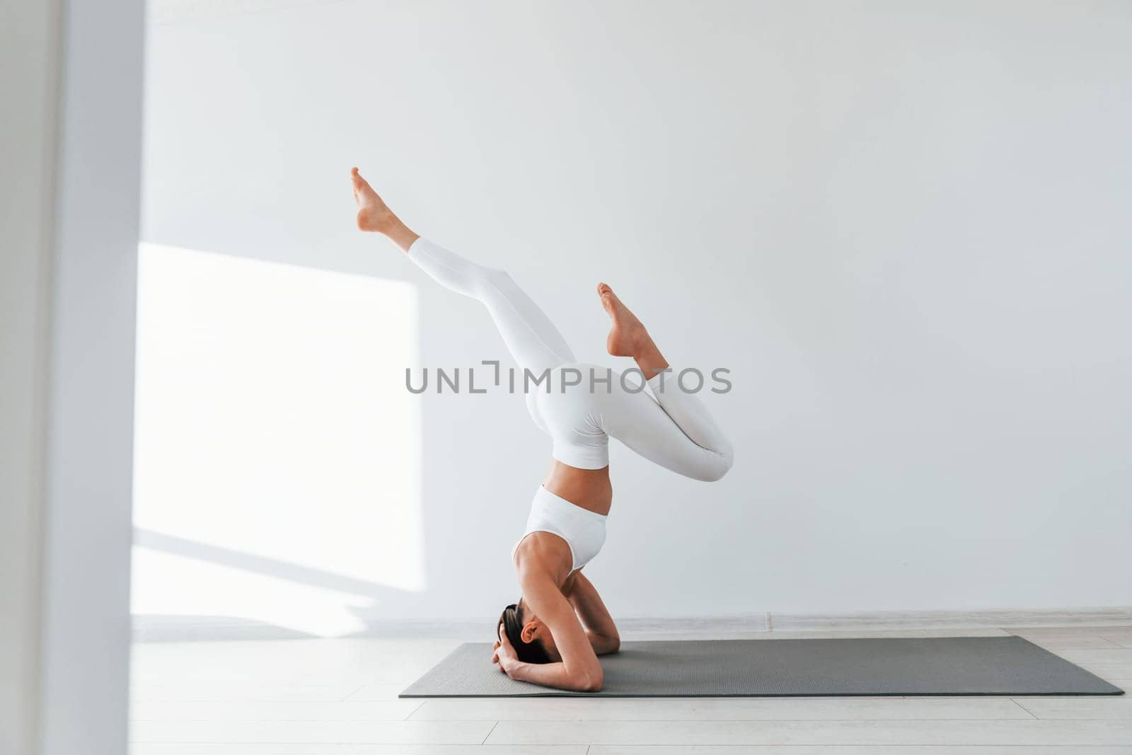 Doing exercises. Young caucasian woman with slim body shape is indoors at daytime.