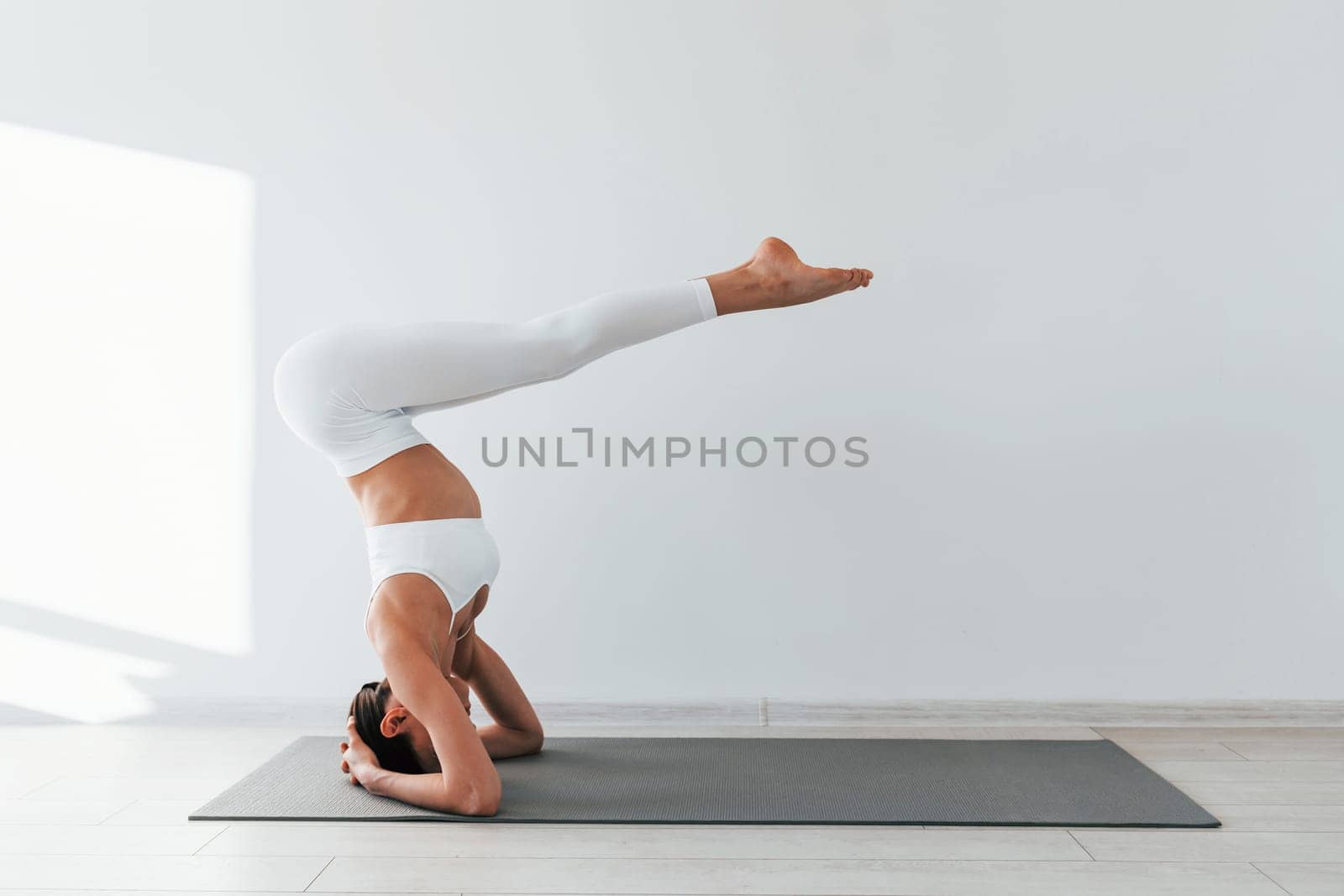 Doing exercises. Young caucasian woman with slim body shape is indoors at daytime by Standret