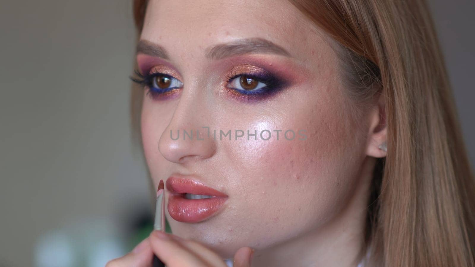 Makeup artist paints lips of a model girl