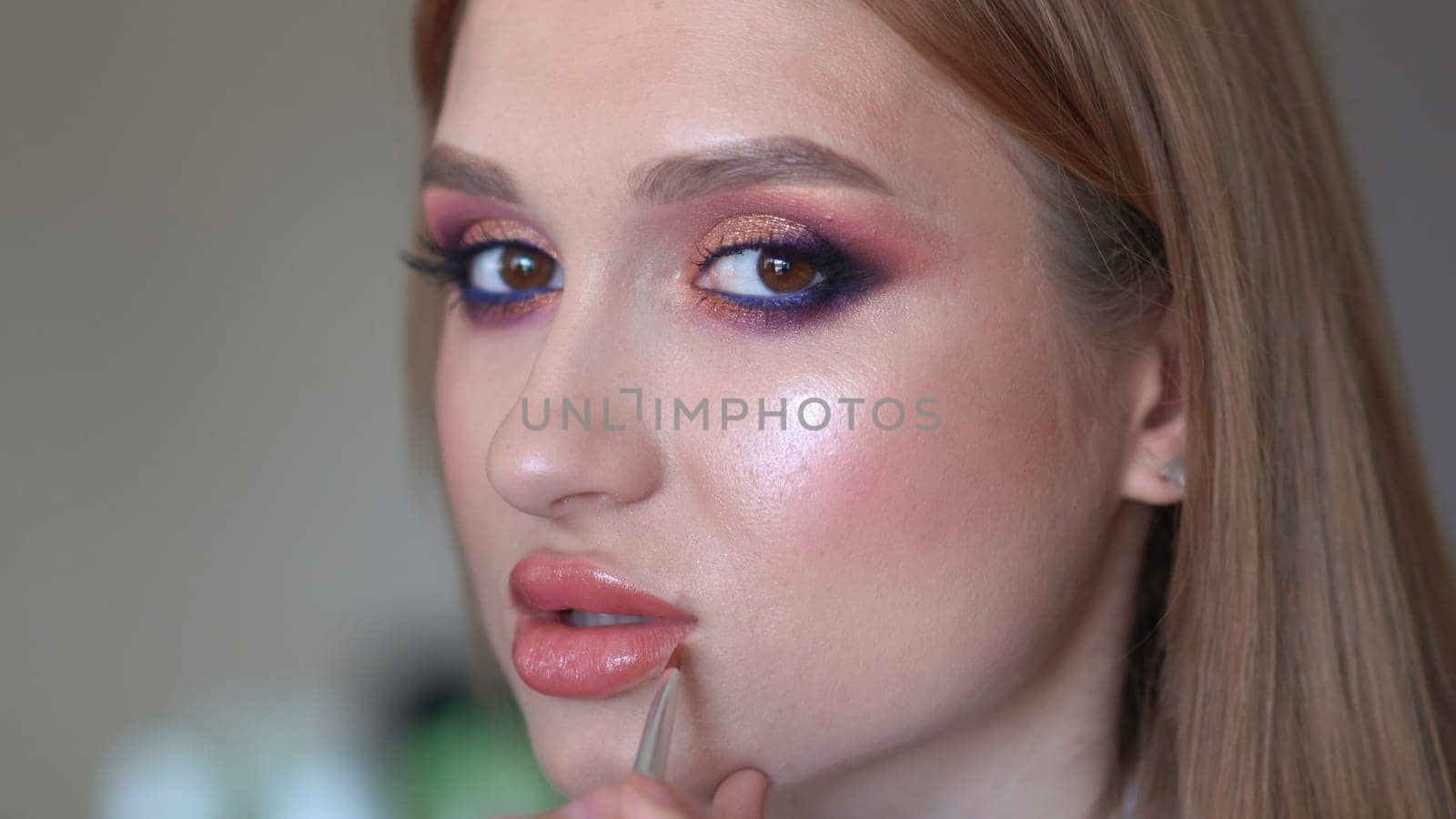 Makeup artist paints lips of a model girl. by DovidPro