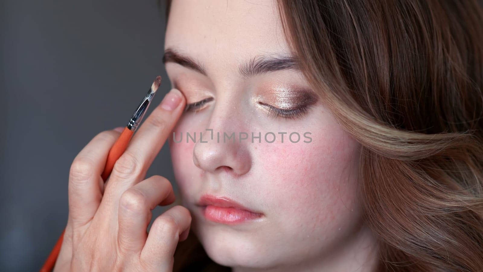 Makeup artist paints eyelids on a model girl