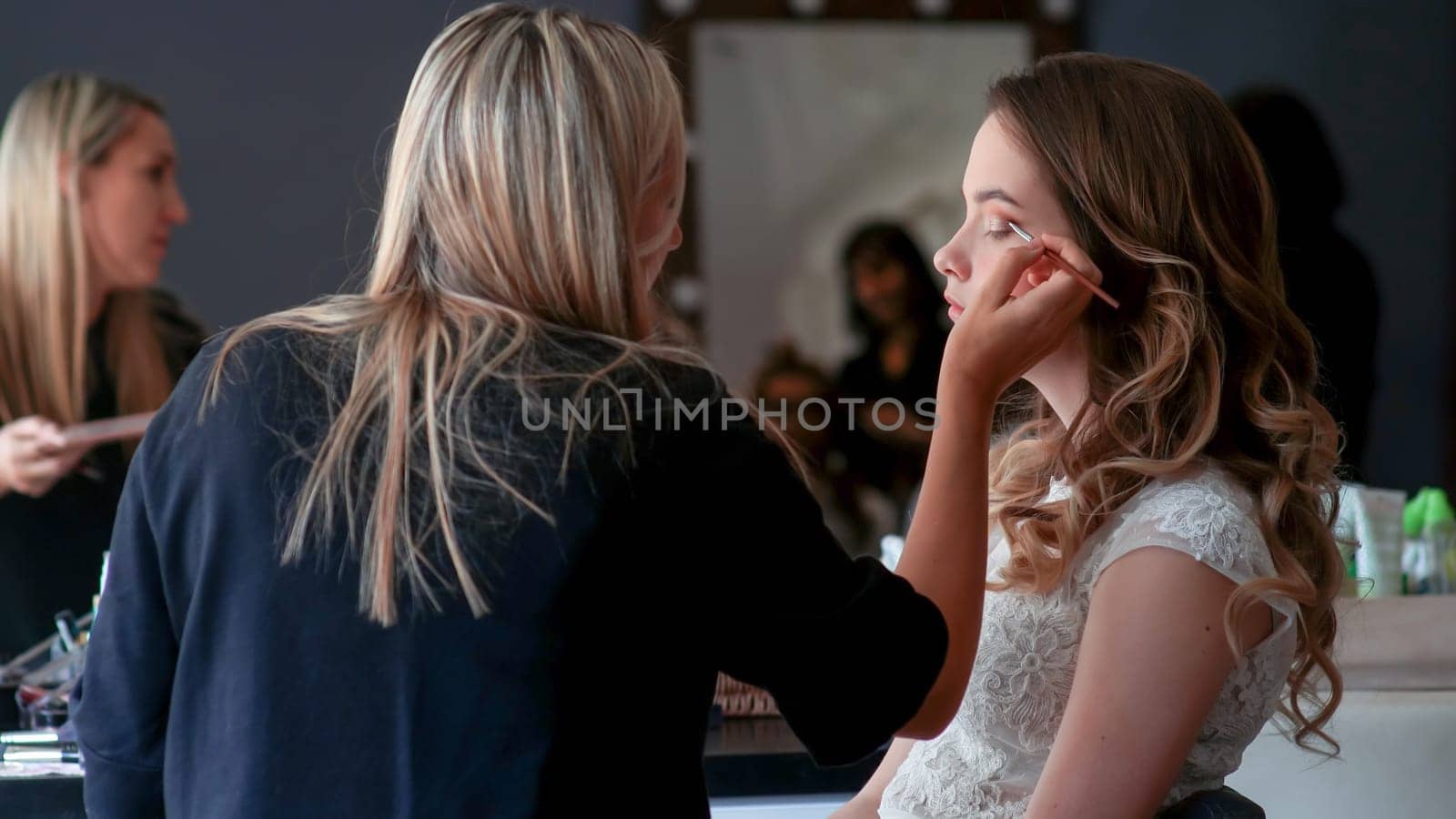 Makeup artist paints the eyes of a girl model.