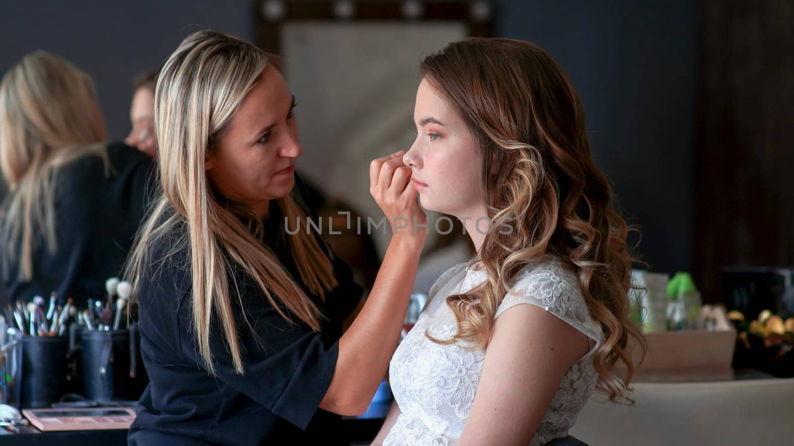 Makeup artist paints the eyes of a girl model.